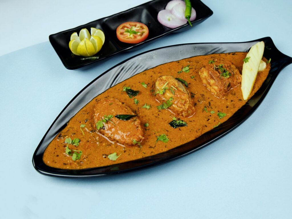 Tantalizing Indian curry with seafood served in a stylish dish, accented by fresh ingredients.