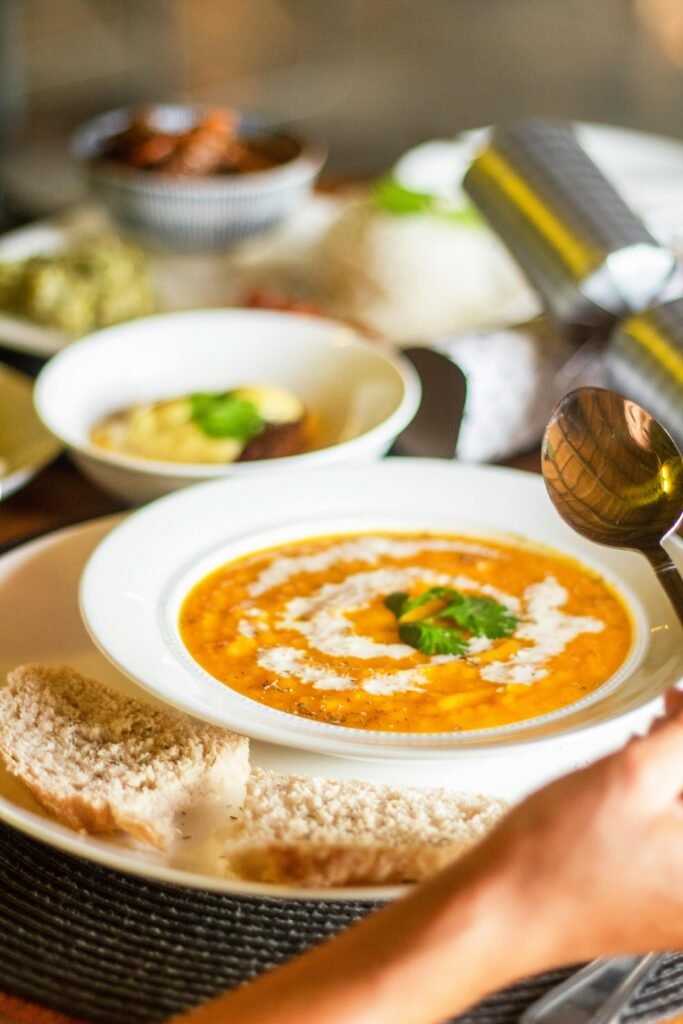 Close-up of creamy Indian lentil soup with a swirl of cream and cilantro garnish served with bread.